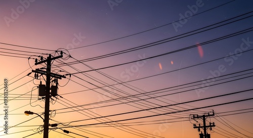 Silhouette of power lines and utility poles against a vibrant sunset sky.