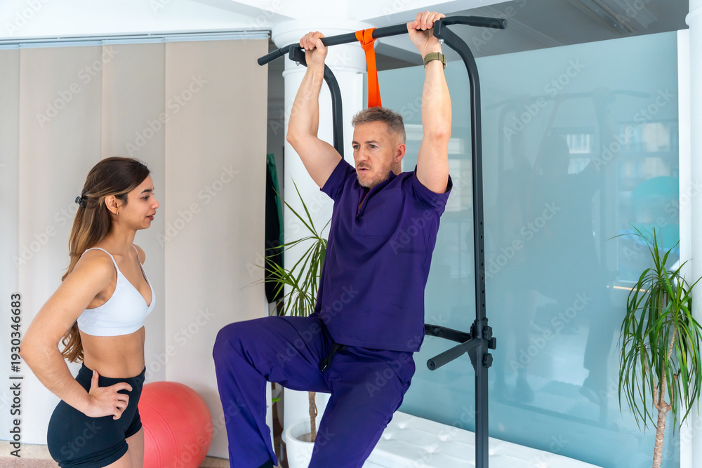 Fototapeta premium Man performing physical therapy exercise assisted by physiotherapist