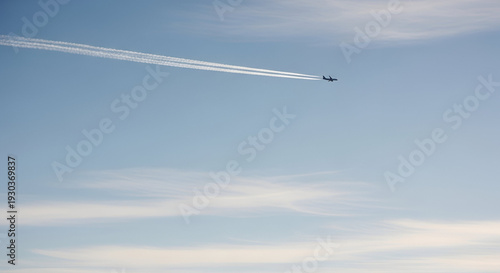 A large commercial passenger jet airplane is captured in silhouette, flying gracefully across a vast, clear blue sky, leaving a pair of long, parallel white contrails trailing distinctly behind it, cr