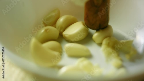 Person is squeezing the peeled garlic cloves in a bowl