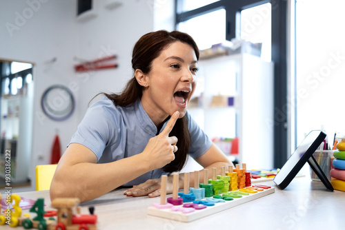 Foto Speech therapist demonstrating oral motor exercises while providing teletherapy