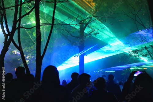 Lasers at music festival with people shadows and hands with smartphones in the air