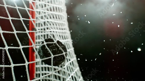 Super slow motion of ice hockey puck hitting the back of the net as it scores a goal