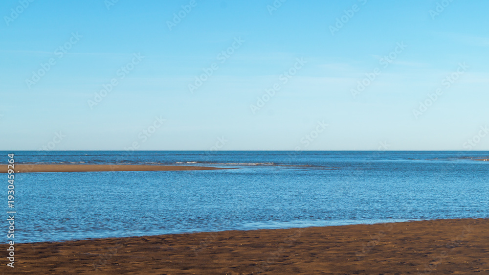 Fototapeta premium View of the ocean, sea from the beach with yellow, orange sand. Sea bay. View of the sea horizon on a sunny, clear day