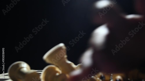 White chess pieces on a black background stand in a row, and the chess player's hand passes over them, knocking them down onto the game board. 4к
