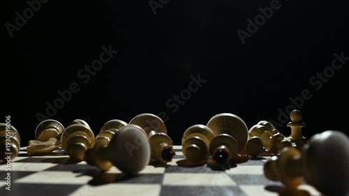 White chess pieces on a black background stand in a row, and the chess player's hand passes over them, knocking them down onto the game board. 4к