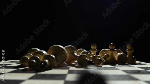 White chess pieces on a black background stand in a row, and the chess player's hand passes over them, knocking them down onto the game board. 4к