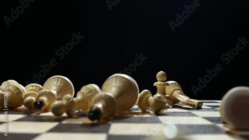 White chess pieces on a black background stand in a row, and the chess player's hand passes over them, knocking them down onto the game board. 4к