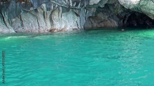 Marvel at Patagonia's wondrous Marble Caves, gleaming with sculpted white and gray patterns. Pristine turquoise waters of General Carrera Lake reflect the majestic natural artistry on a bright day.
