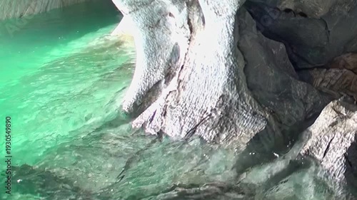 Gaze upon the breathtaking natural artistry of the Marble Caves in Patagonia. Sun-drenched turquoise waters gently lap against ancient, sculpted rock formations, revealing a serene, hidden world.