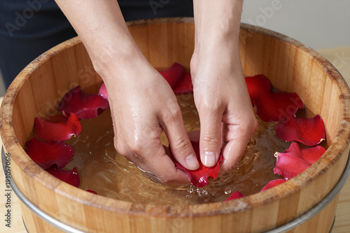 Wallpaper Mural Hands Gently Washing Red Rose Petals in Wooden Bucket Filled with Water for Spa or Relaxation Treatment Torontodigital.ca