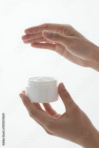 Wallpaper Mural Hands Holding White Jar of Skincare Cream with Dollop on Top Against Clean Minimalist Background for Beauty or Wellness Product Use Torontodigital.ca