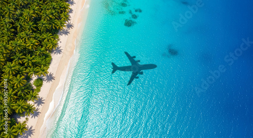 Aerial shot of tropical beach with turquoise ocean and palm trees. Plane shadow over water, representing travel, vacation and destination concept.