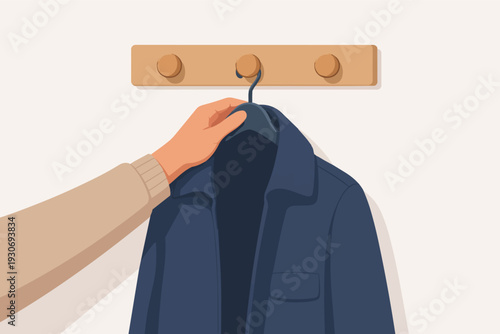 Hand hanging blue jacket on coat hook, organizing clothes in a home hallway