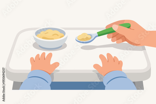 Baby hands on high chair tray receiving first solid foods from a spoon