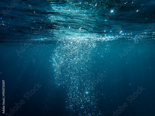 Underwater background with water bubbles and undersea light rays shine. Dark blue ocean surface seen from underwater. Sunbeams and Sea deep or ocean underwater a  Abstract background. sunlight Nature.