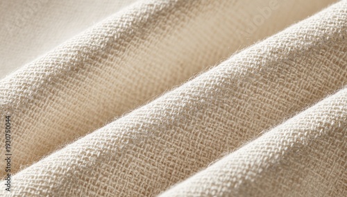 Close-up of beige woven fabric, showing texture and folds. Light and shadow enhance the details