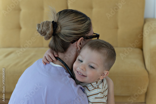 Female nurse hugging toddler child at home, pediatric healthcare and family medicine concept
