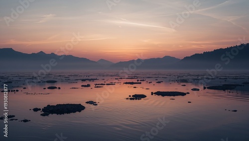 Sunset Over a Calm Water Body With Mountains and Floating Rocks in the Backgr...