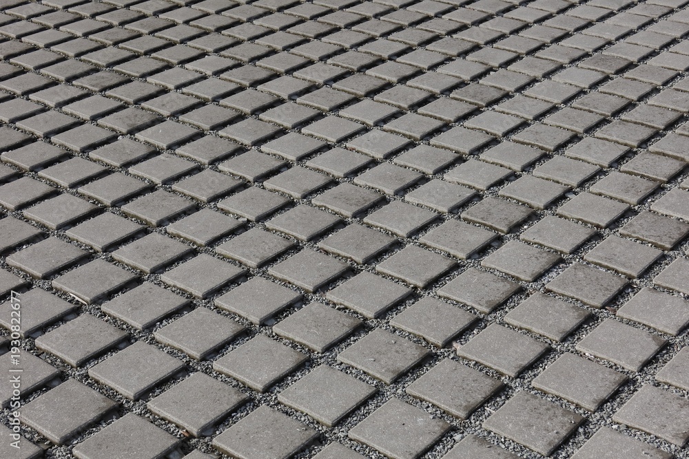 Fototapeta premium Close-up of grey square pavers laid in a grid. Graphics texture, background.