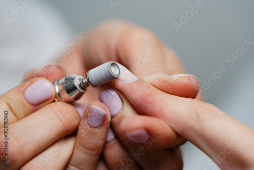 Vászonkép A close-up view of a professional nail technician using an electric milling cutter to shape and file a client's fingernails during a manicure treatment in a beauty salon