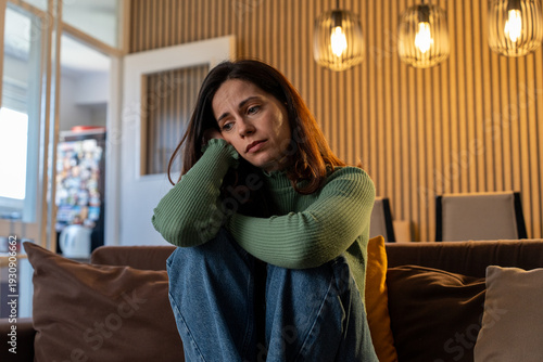 Young female feeling down, sitting on couch, overwhelmed by life pressure