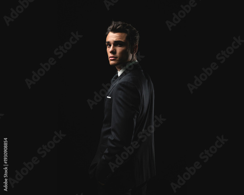 Confident young man in formal suit turning around