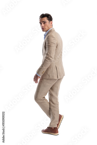 Back view of confident man walking and looking back