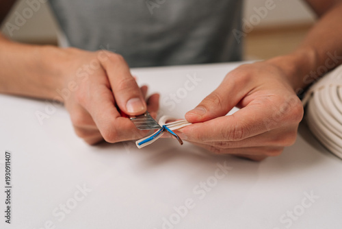 Billede på lærred Close-up cropped shot electrician hands splitting modern data cable using cutter