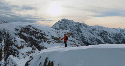 Ski mountaineer standing on a snowy cliff in the Dolomites with majestic alpine peaks in the background, capturing winter adventure, solitude and breathtaking mountain scenery.