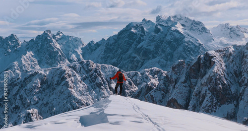Ski mountaineer standing on a snowy cliff in the Dolomites with majestic alpine peaks in the background, capturing winter adventure, solitude and breathtaking mountain scenery.