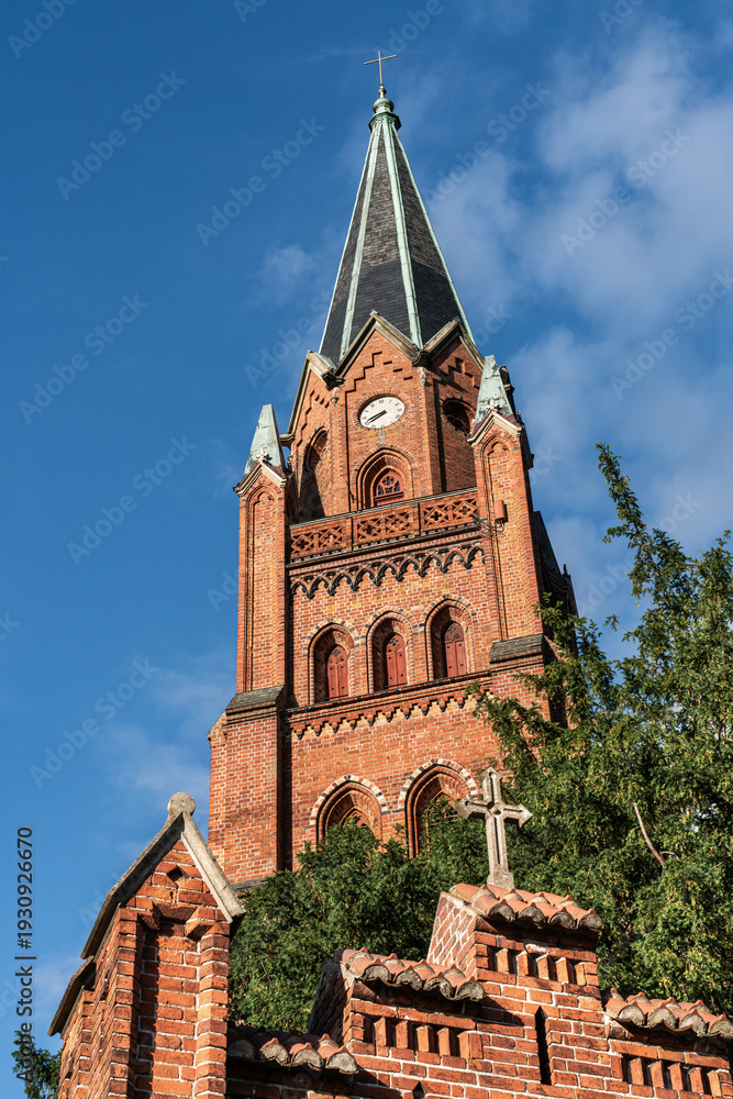 Fototapeta premium Church tower of St. Mary’s Church in Röbel/Müritz, Germany, sunlit facade with blue sky. Historic landmark in Mecklenburg-Western Pomerania.