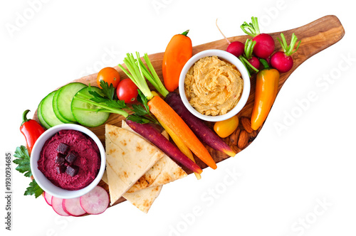 Assortment of fresh vegetables and hummus dip on a serving board. Top view isolated on a white background.