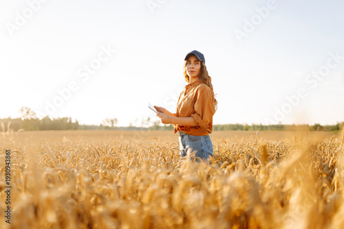 Billede på lærred A young farmer with a digital tablet works in a golden wheat field on a sunny day