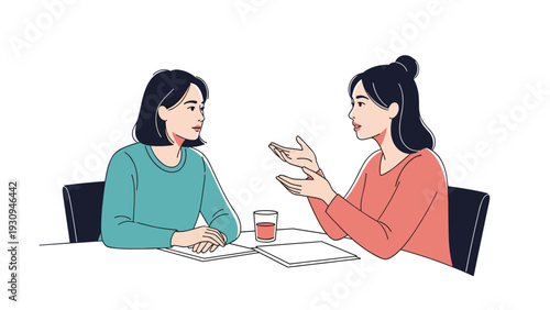 Two young women sitting at a table with drinks and documents having a serious or friendly conversation in a cafe or office setting.