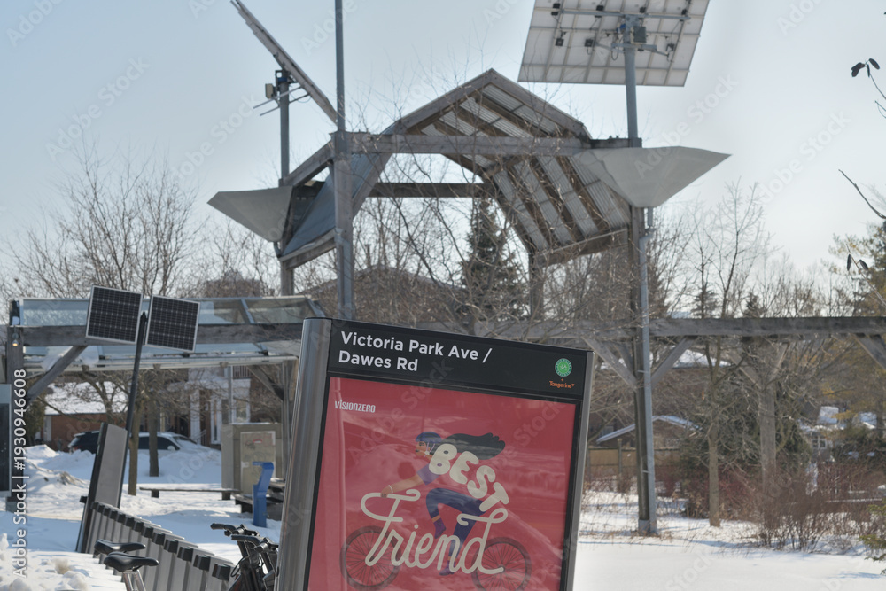 Fototapeta premium Bike Share Toronto docking station at Victoria Park Av and Dawes Road - behind is Dawes Crossing, a barn-like structure, honoring area's rural past