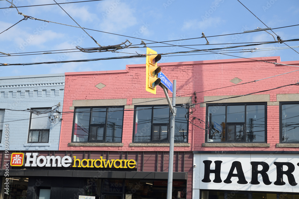 Fototapeta premium exterior building facade and signs of Pat's Home Hardware and Harry's Charbroiled, a fast food restaurant, located on Coxwell Av north of Gerrard St E, Toronto