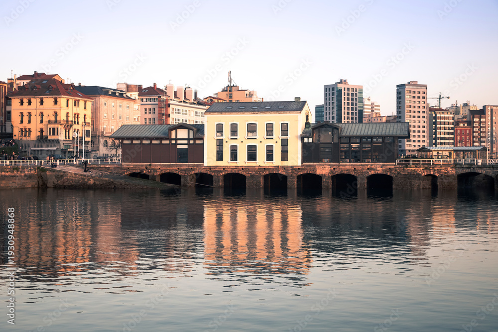 Obraz premium Cityscape of Gijon with Waterfront Buildings and Reflections at Daytime. Asturias, Spain.