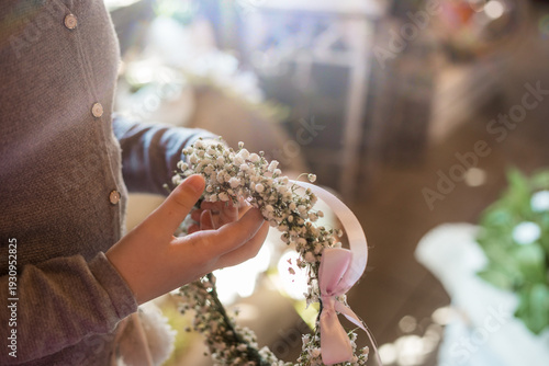Girl holding delicate First Communion floral headband with fresh gypsophila