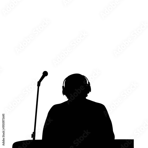Silhouetted speaker wearing headphones at podium with microphone