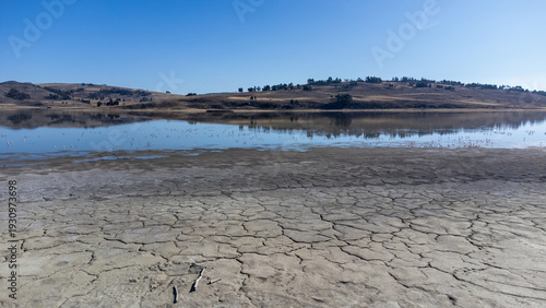 Wide panoramic view of the arid Andean Altiplano with a lake and mountains.