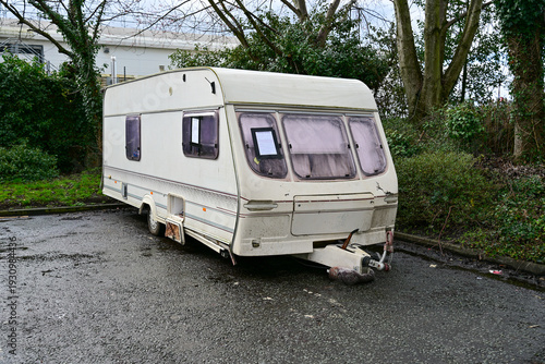 A damaged and broken caravan trailer is parked in a parking lot