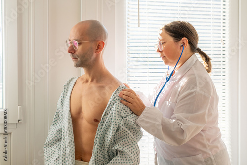 Billede på lærred female doctor using stethoscope listen male patient's chest, doctor performing a