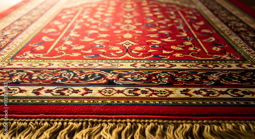 A detailed, close-up view of a richly patterned red and gold Persian rug with intricate floral designs and fringed edges