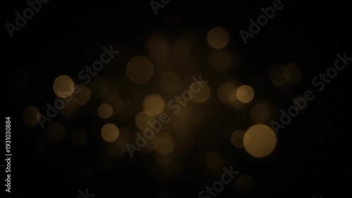 Shimmering golden-yellow bokeh lights appear, multiply, and glow brightly against a dark background before slowly dimming and disappearing.