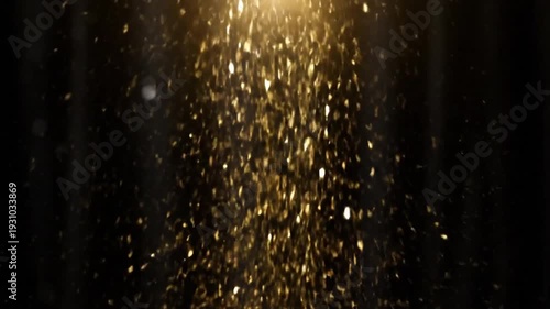A dazzling stream of golden, shimmering particles gracefully falls downwards against a dark, subtle background, illuminated by a bright light source from above.