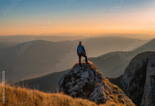 A man who enjoys hiking takes a break look at the top of the mountain at sunset adventure travel.