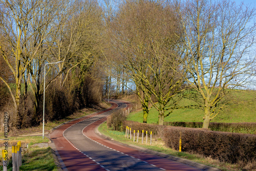 Winter landscape, Countryside road with bare trees and green grass on slope hillside, The Dutch province of Limburg, Margraten is a village and a former municipality in the southeastern, Netherlands.