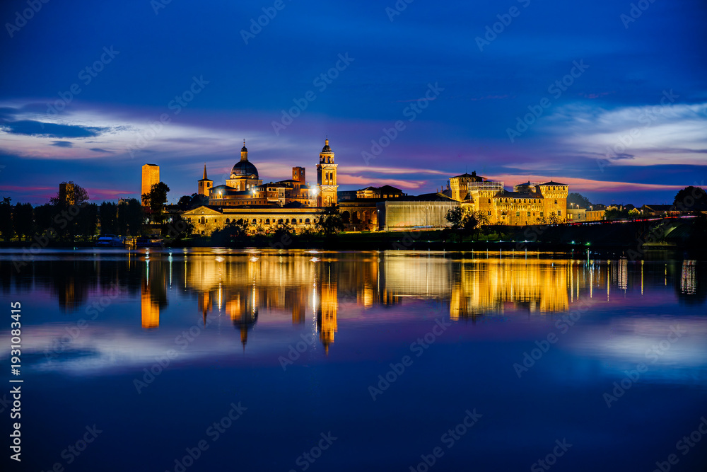 Fototapeta premium Panoramic evening view of Mantua, Lombardy, Italy; scenic twilight skyline view of the medieval town reflected in the lake waters