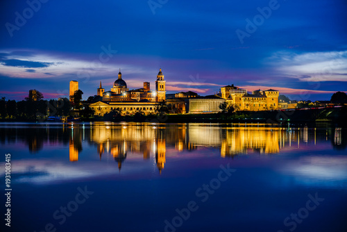 Panoramic evening view of Mantua, Lombardy, Italy; scenic twilight skyline view of the medieval town reflected in the lake waters